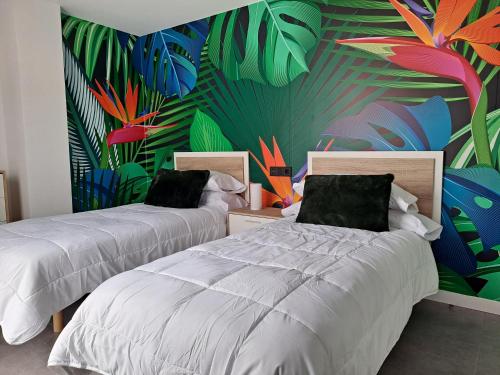 贝尼多姆LEVANTE SUITES的一间卧室设有两张床,并拥有植物壁画