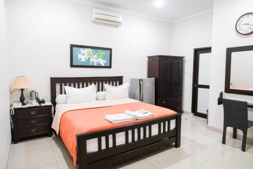 棉兰Pasola Guest House的一间卧室配有一张床、一张书桌和一台电视。