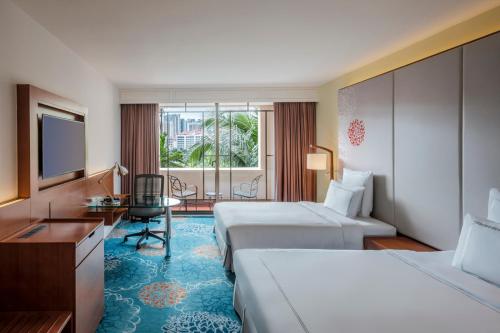 新加坡Paradox Singapore Merchant Court at Clarke Quay的酒店客房设有两张床、一张桌子和一台电视。