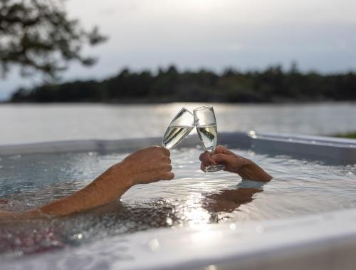 埃克勒卡琳松德度假酒店的在游泳池里拿着两杯葡萄酒的人