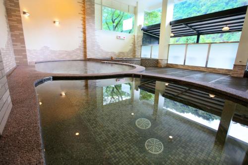 乌来乌来Spring Spa温泉山庄的水中反射的建筑物中的游泳池
