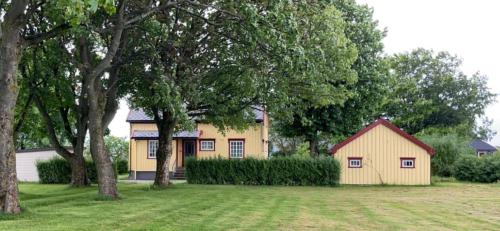 布雷克斯塔德Sjarmerende hus med veldig stort uteareal.的一座小黄房子,在院子里有树