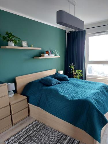 格但斯克Apartament przy stadionie的一间卧室设有一张床和蓝色的墙壁