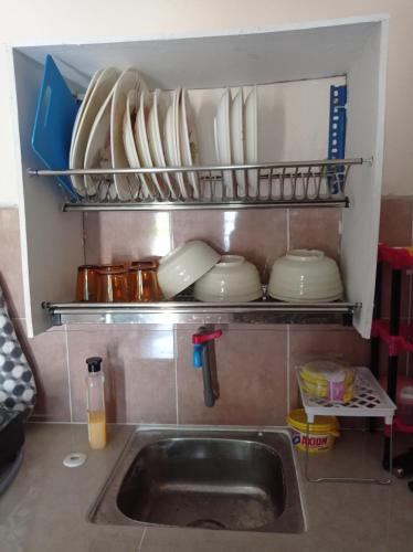 PakaBonda Guesthouse III的厨房水槽,架子上摆放着盘子和盘子