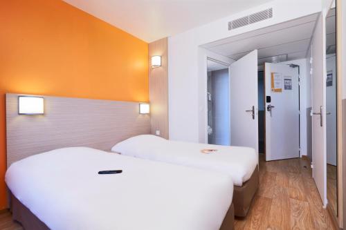 梅里尼亚克波尔多西部 - 梅里尼亚克机场普瑞米尔经典酒店的橙色墙壁客房的两张床