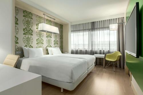 阿姆斯特丹南阿姆斯特丹NH酒店的酒店客房设有一张白色大床和一张书桌