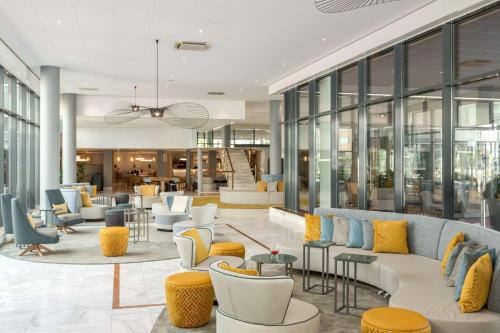 霍夫多普阿姆斯特丹史基浦机场NH酒店的大堂配有沙发、桌子和窗户。