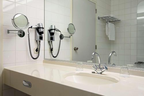 艾瑟尔河畔卡佩勒鹿特丹卡佩里NH酒店的浴室设有水槽,镜子上配有两部电话