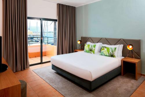 波尔蒂芒NH Marina Portimao Resort的一间带大床的卧室和一个阳台