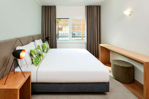 波尔蒂芒NH Marina Portimao Resort的一间卧室设有一张大床和一个窗户。