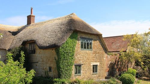 伊尔明斯特Courtyard Cottage at Stepps House的一座带茅草屋顶的古老石头房子