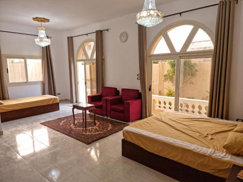 Abû Zeiraفيلا العيلة Villa L-3eela的一间卧室设有两张床、一把椅子和一个窗户。