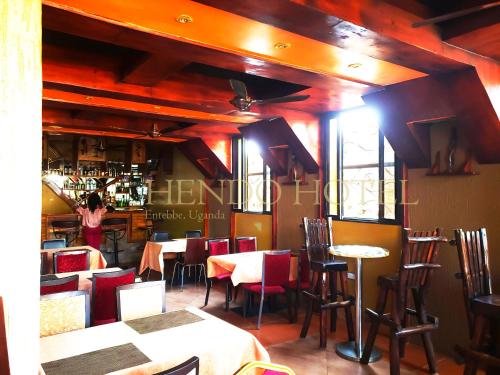恩德培Hendo Hotel的一间设有桌椅的餐厅,一名妇女站在酒吧