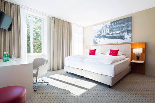 温特图尔Hotel Wartmann am Bahnhof的酒店客房配有一张带红色枕头的大床