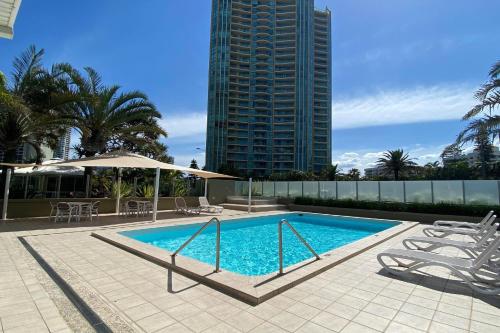 黄金海岸海冲浪海滨度假公寓酒店的一座带椅子的游泳池,一座高高的建筑