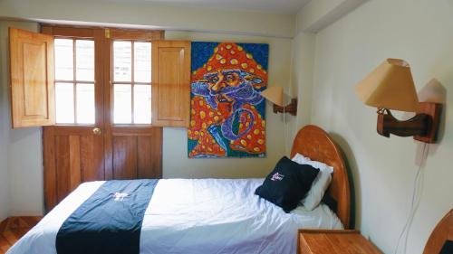 皮萨克Colores Hotel Apu-Linli的卧室配有一张床,墙上挂有绘画作品