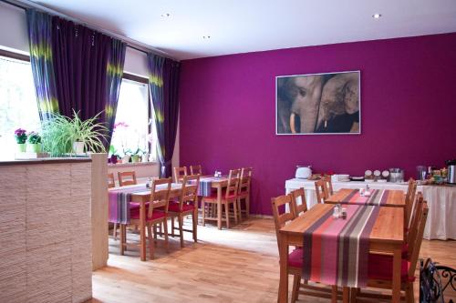 柏林贝尔酒店 的餐厅拥有紫色的墙壁和木桌及椅子