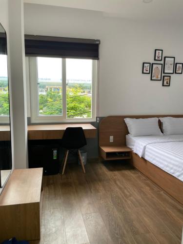 岘港Airport homestay的一间卧室配有一张床、一张书桌和两个窗户。