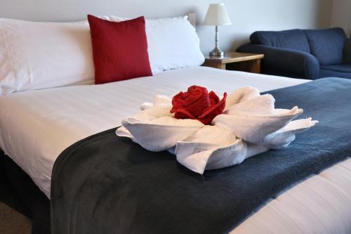 提马鲁贝沃奇汽车旅馆旅舍的一张白色的床,上面有红玫瑰