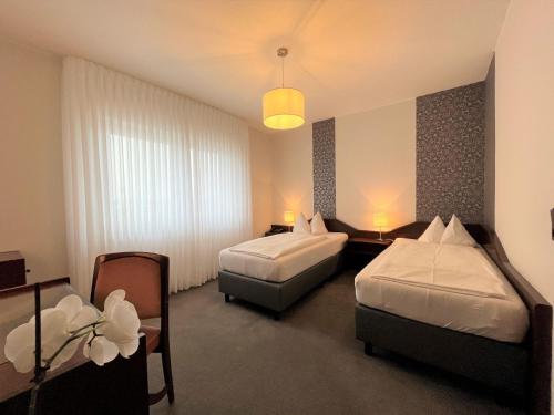 科隆Hotel Garni Geisler的酒店客房设有两张床和一张桌子。