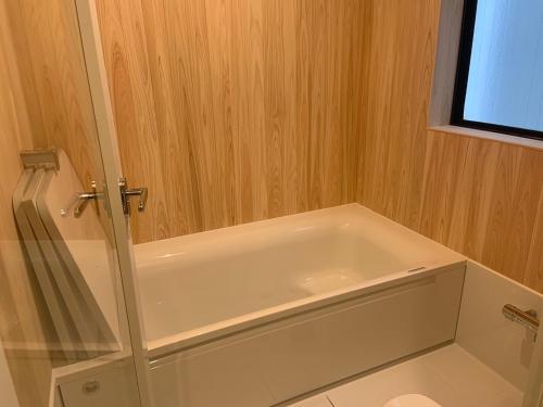 横滨Yokohama HY House的浴室设有白色浴缸,拥有木墙