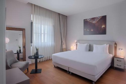 佛罗伦萨佛罗伦萨罗萨港NH精选酒店的卧室配有一张白色大床和一把椅子