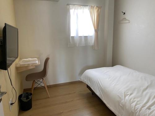 日向ゲストハウスHINATA的一间卧室配有一张床、一台电视和一把椅子