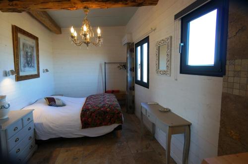 圣马迪拉莫Gîtes Equestres Lou Caloun - Les Saintes Maries de la Mer的一间卧室配有一张床、一张桌子和一个吊灯。