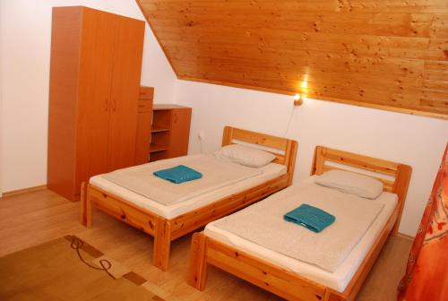 福纽德Kék Kuckó Vendégház的木天花板客房的两张单人床