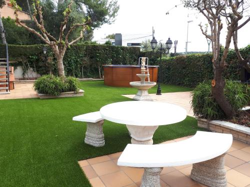 塔拉戈纳Family House - La Mora Beach - Tarragona的花园设有2张白色桌子和喷泉
