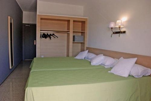 罗列特海岸Hotel Armonía的一间卧室配有带白色枕头的绿色床
