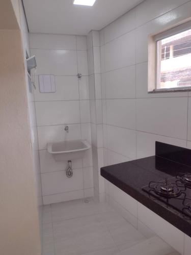 瓜拉派瑞Praia de Setiba - Kitnet的白色瓷砖浴室设有水槽和台面