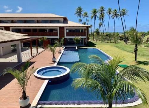 伊塔齐米林Apto Novo beira-mar Praia de Itacimirim的一座带游泳池和棕榈树的房子