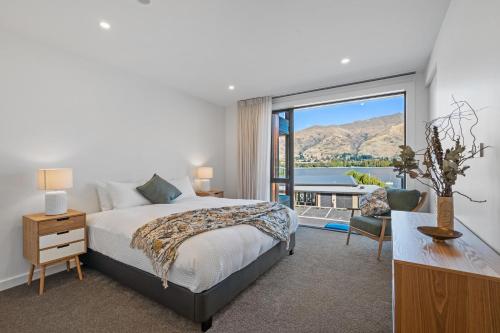 瓦纳卡Winona of Wanaka - Luxury Lakefront Apartment的一间卧室设有一张床和一个大窗户