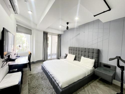 古尔冈BedChambers Serviced Apartments - Cyber City的一间卧室配有一张床、一张书桌和一个窗户。