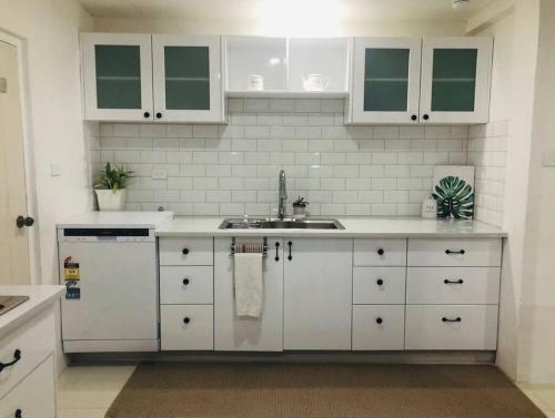 苏瓦Suva City Accommodation的厨房配有白色橱柜和水槽