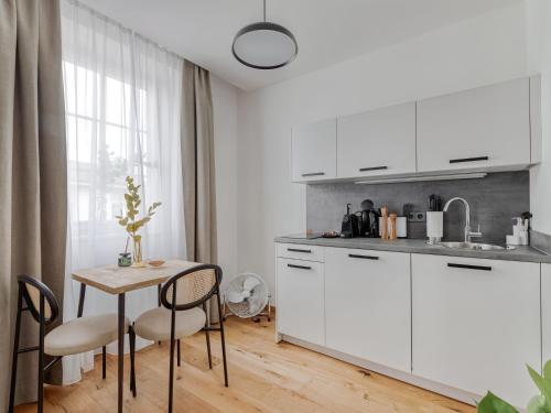 菲拉赫limehome Villach Gerbergasse的厨房配有白色橱柜和桌椅