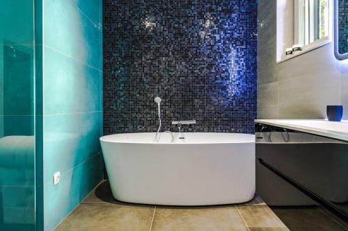 斯普利特Luxury apartment Martinis with pool的浴室设有浴缸,铺有蓝色瓷砖。
