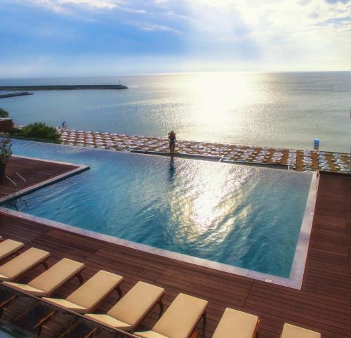 金沙GRIFID Encanto Beach Hotel - MediSPA, Ultra All Inclusive & Private Beach的一个带椅子的游泳池,背景是大海