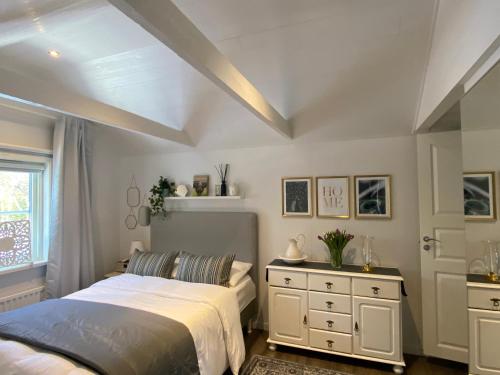 东哈尔马Carpe Diem Guest Cottage的一间卧室配有一张床、一个梳妆台和一扇窗户。