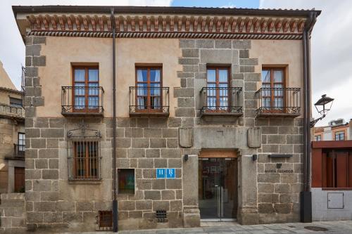 阿维拉María Pacheco Hotel Boutique的一座古老的石头建筑,设有窗户和阳台