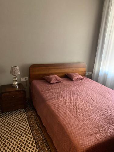 考纳斯Cathedral Apartments的一间卧室配有带粉色床单和台灯的床