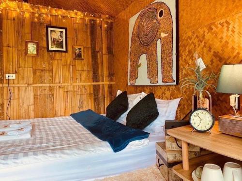 Ban Mae Sapok Noi3 Pok Maewang jinxiang Gold elephant park的一间卧室配有一张床和一张桌子上的闹钟