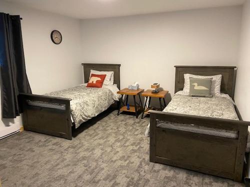 丘吉尔Bears Den Guest House的一间卧室设有两张床,墙上挂着一个时钟。