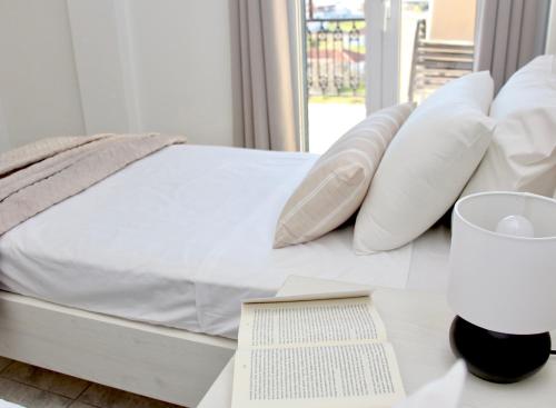 阿利卡纳斯Lightful Attic at Regina Apartments的一张带白色枕头的床和一张桌子上的书