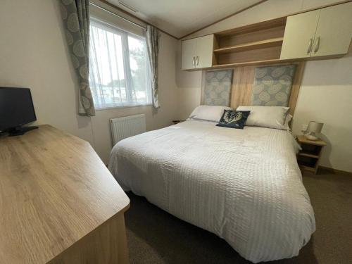 博特夫加滕'Oakley' Boat of Garten Holiday Park的卧室设有一张白色大床和一扇窗户。