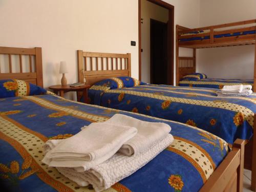 苏萨AGRITURISMO Cré Seren的一间卧室配有三张床和毛巾