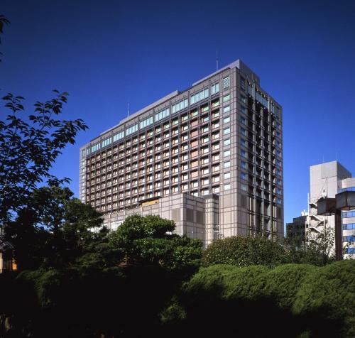京都Hotel Okura Kyoto的一座高大的玻璃建筑,前面有树木