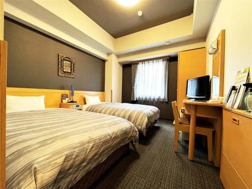 福冈Hotel Route-Inn Hakata Ekimae -Hakataguchi-的酒店客房设有两张床和一张书桌及电视