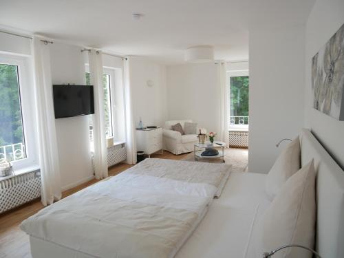 魏因海姆富克斯磨酒店的一间白色的卧室,配有一张大床和一个客厅